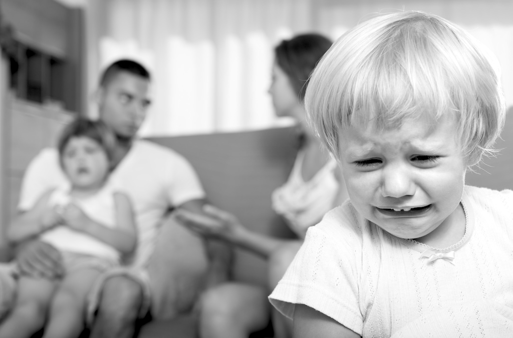 Young married couple with two little daughters having quarrel at home